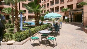 Un cortile con piscina, palme e area relax all'aperto.