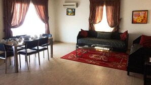 Ein Wohnzimmer mit Essplatz, einer Couch und einem roten Teppich.