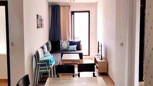 Un espacio habitable compacto con sofá, mesa de comedor, sillas y televisor.