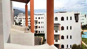 Vista de una zona residencial con edificios blancos, balcones y cielo despejado.