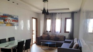 A modern living room with a glass dining table, grey sofas, and a coffee table. - Residence Lilac's Garden 5160 (Cabo Negro)