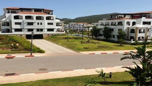 A modern hotel with multiple white buildings, a central road, and surrounding greenery. - Residence Lilac's Garden 5160 (Cabo Negro)