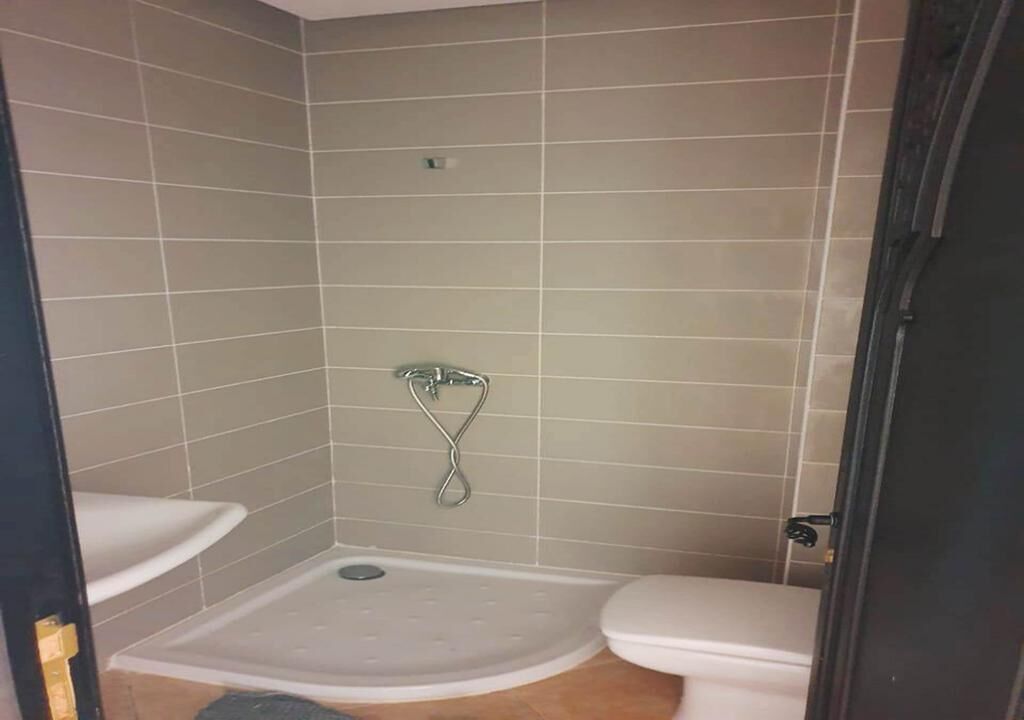 Ein kleines Badezimmer mit Dusche, Toilette und Waschbecken.