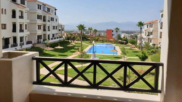 A residential area with a swimming pool, palm trees, and a view of mountains. - Residence Lilac's Garden 5160 (Cabo Negro)
