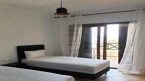 A bedroom with two beds, a ceiling light, and a sliding glass door to a balcony. - Residence Lilac's Garden 5160 (Cabo Negro)