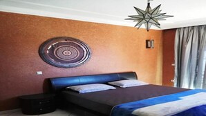 Un dormitorio con una cama, una mesita de noche, un adorno circular en la pared y una lámpara colgante con forma de estrella.