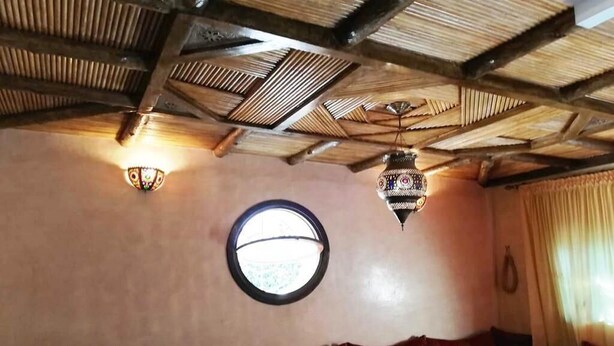 Una habitación con un ventanal redondo, un sofá rojo y una mesa redonda.