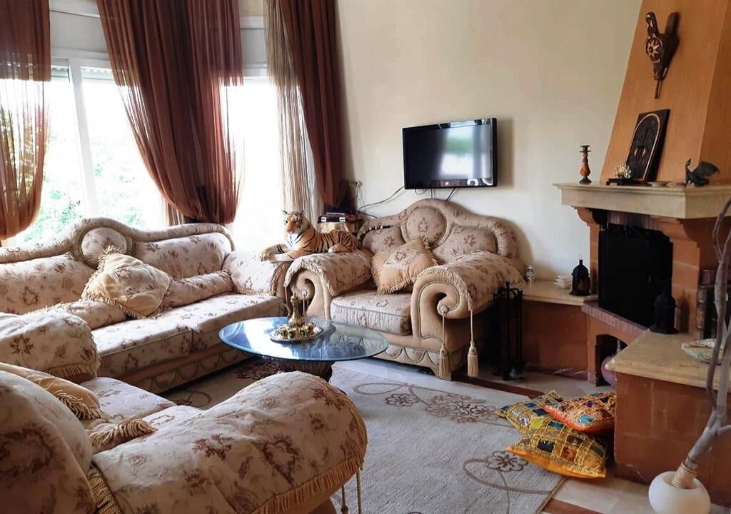 A living room with a sofa set, a coffee table, a fireplace, and a television mounted on the wall.