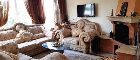 A living room with a sofa set, a coffee table, a fireplace, and a television mounted on the wall.