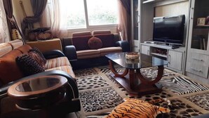 A living room with a sofa, a coffee table, a television, and a tiger plush toy on the floor. - Large Beachfront Villa in Sonaba Agadir 5164 (Agadir)