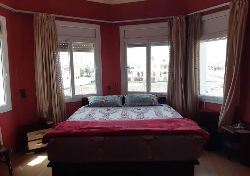 Quarto com uma cama grande, duas janelas e vista para o exterior.
