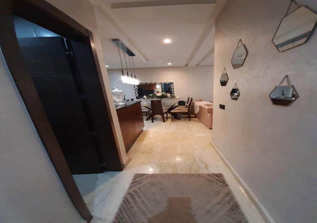 A modern interior with a dining area, kitchen, and a hallway leading to a dark door.