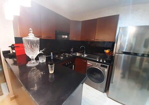 Una cocina moderna con electrodomésticos de acero inoxidable, encimera negra y armarios de madera.