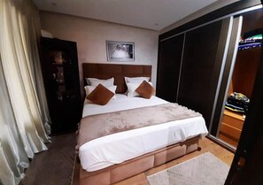 Una habitación de hotel con una cama grande, cabecera, armario y armario con puerta corredera.