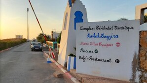 Schild für eine Wohnanlage mit Annehmlichkeiten wie Mini-Villen, einem Pool und einem Café-Restaurant.