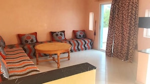A living room with a sofa set, a round wooden table, and patterned cushions.