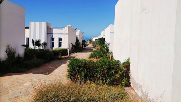 A narrow pathway flanked by white buildings with a clear blue sky above. - Complex Kasbah Lagzira 5203 (Sidi Ifni)