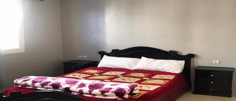 A bedroom with a bed, two nightstands, and a window.