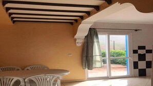 Ein Zimmer mit Esstisch und Stühlen, einer Schiebetür zu einem Außenbereich und einem Schachbrettmuster auf dem Boden.