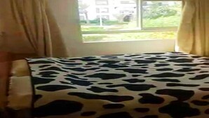 Ein Zimmer mit Bett, Fenster und Vorhängen.