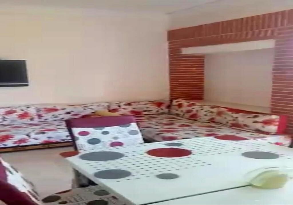 Ein Zimmer mit einer Sofagarnitur, einem Tisch mit einem Tischleinenschal in Punkteoptik und einer Wand mit Ziegeln als Blickfang.