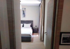 Quarto de hotel com uma cama, mesa de cabeceira e um quadro na parede.