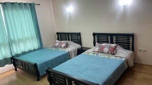 A room with two beds, each with a blue bedspread and patterned pillows. There are two wall-mounted lights and a window with curtains. - Residence Marina Agadir 5218 (Agadir)