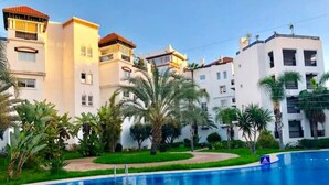 A swimming pool surrounded by lush greenery and white buildings with balconies. - Residence Marina Agadir 5218 (Agadir)