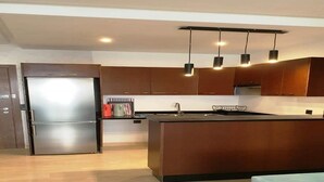 A modern kitchen with a central island, stainless steel refrigerator, and pendant lighting. - Residence Hivernage Founty 5227 (Agadir)