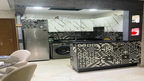 Une cuisine compacte équipée d’un lave-linge, d’un réfrigérateur et d’un crédence décorée.