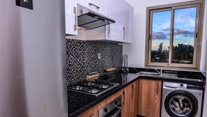 A modern kitchen with a gas stove, oven, and built-in washing machine. - Residence Marrakech Prestigia Golf City 5244 (Marrakech)