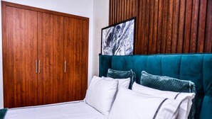 A bedroom with a large wooden wardrobe, a teal upholstered headboard, and a framed picture above the bed. - Residence Marrakech Prestigia Golf City 5244 (Marrakech)