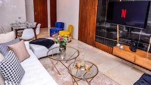 A modern living room with a sofa, two chairs, a coffee table, and a TV mounted on a wall. - Residence Marrakech Prestigia Golf City 5244 (Marrakech)