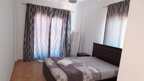 Ein Schlafzimmer mit Bett, Vorhängen, einem Nachttisch und einer Pendelleuchte.