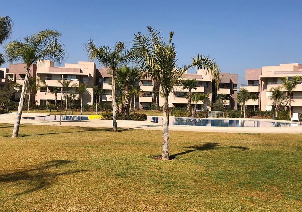 A hotel courtyard with palm trees and a swimming pool.