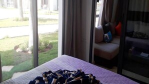 Een hotelkamer met een bed, een slaapbank en een groot raam met uitzicht op de omgeving.