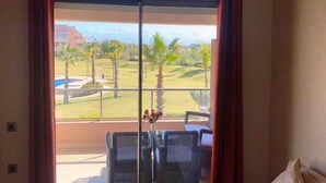 Un balcón con vistas a una zona ajardinada, que incluye palmeras y una piscina.