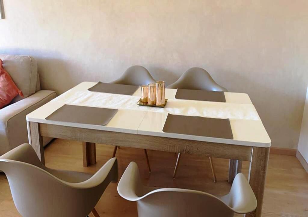 A dining area with a rectangular table, four chairs, and a small table with candles.
