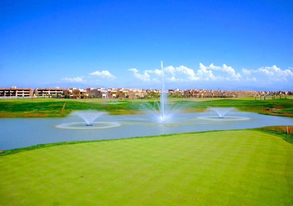 A golf course with multiple fountains and a clear blue sky.
