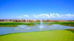 Un campo de golf con numerosas fuentes y un cielo azul despejado.