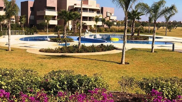 A modern hotel with a swimming pool, palm trees, and a well-maintained lawn. - Residence Marrakech Prestigia Golf City 5304 (Marrakech)