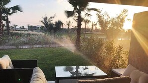 Un área de estar al aire libre con vista a un jardín ajardinado y palmeras.
