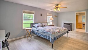 A bedroom with a bed, a desk, a chair, a ceiling fan, and a view of the outdoors. - Possum Kingdom Lakefront Home w/ Patio & Dock! (Graford)