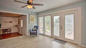 A spacious room with a ceiling fan, a dining area with a wooden table and chairs, and large sliding glass doors leading to an outdoor patio. - Possum Kingdom Lakefront Home w/ Patio & Dock! (Graford)
