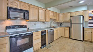 A kitchen with wooden cabinets, a stainless steel refrigerator, a dishwasher, a microwave, and a stove. - Possum Kingdom Lakefront Home w/ Patio & Dock! (Graford)