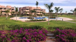 A hotel with multiple buildings, a swimming pool, and lush greenery.