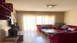 Ein Wohnzimmer mit einem roten Sofa, einem Couchtisch und einer TV-Konsole.