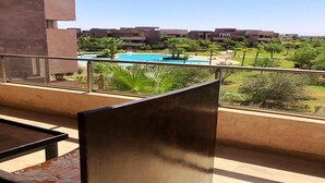 Ein Balkon mit Blick auf einen Pool und die umliegende Grünfläche.