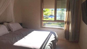Una camera da letto con un letto, una finestra con tende e vista sul verde.