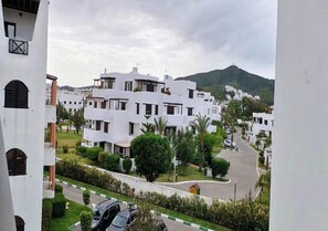 A residential area with white buildings, green lawns, and a hilly background. - Mangle Residence 5331 (Cabo Negro)